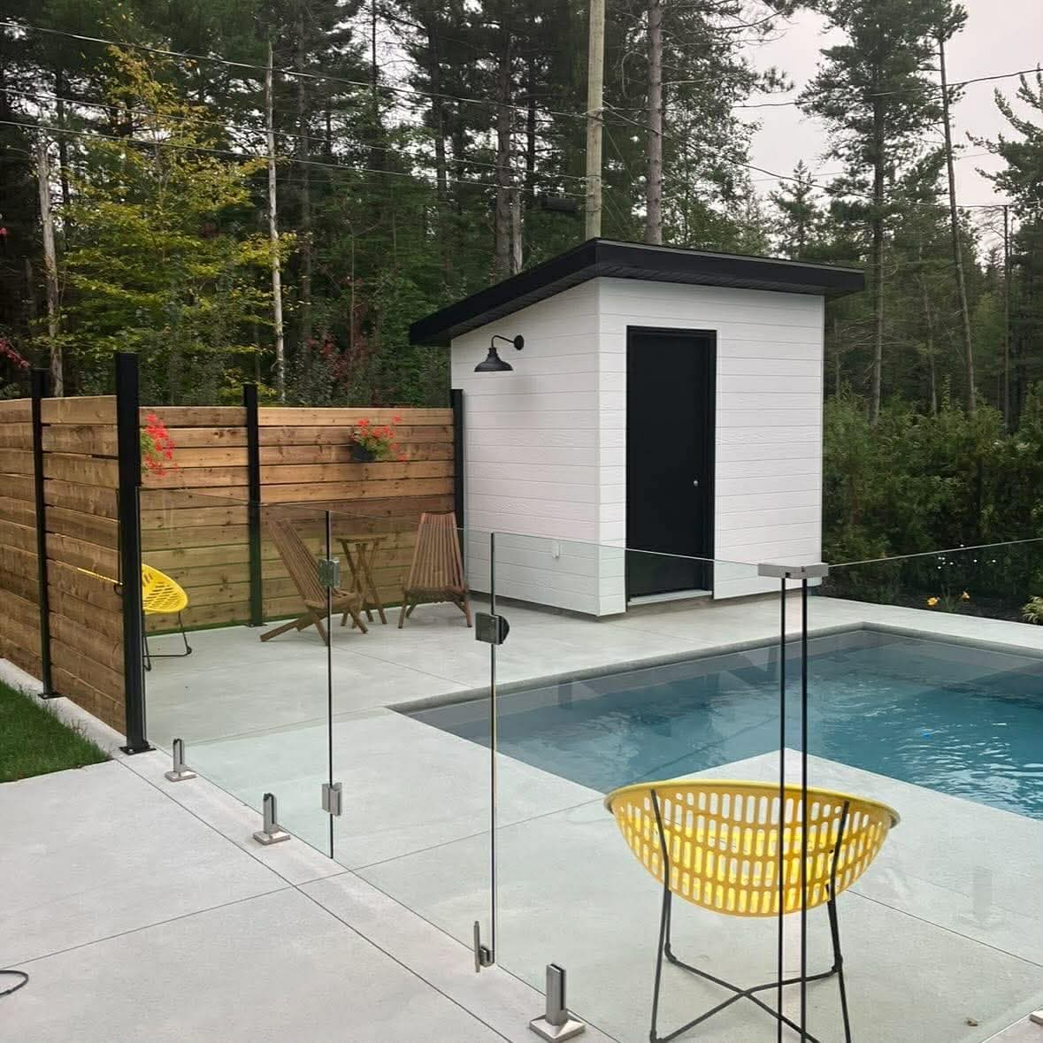 Piscine avec clôture de verre et pavillon blanc